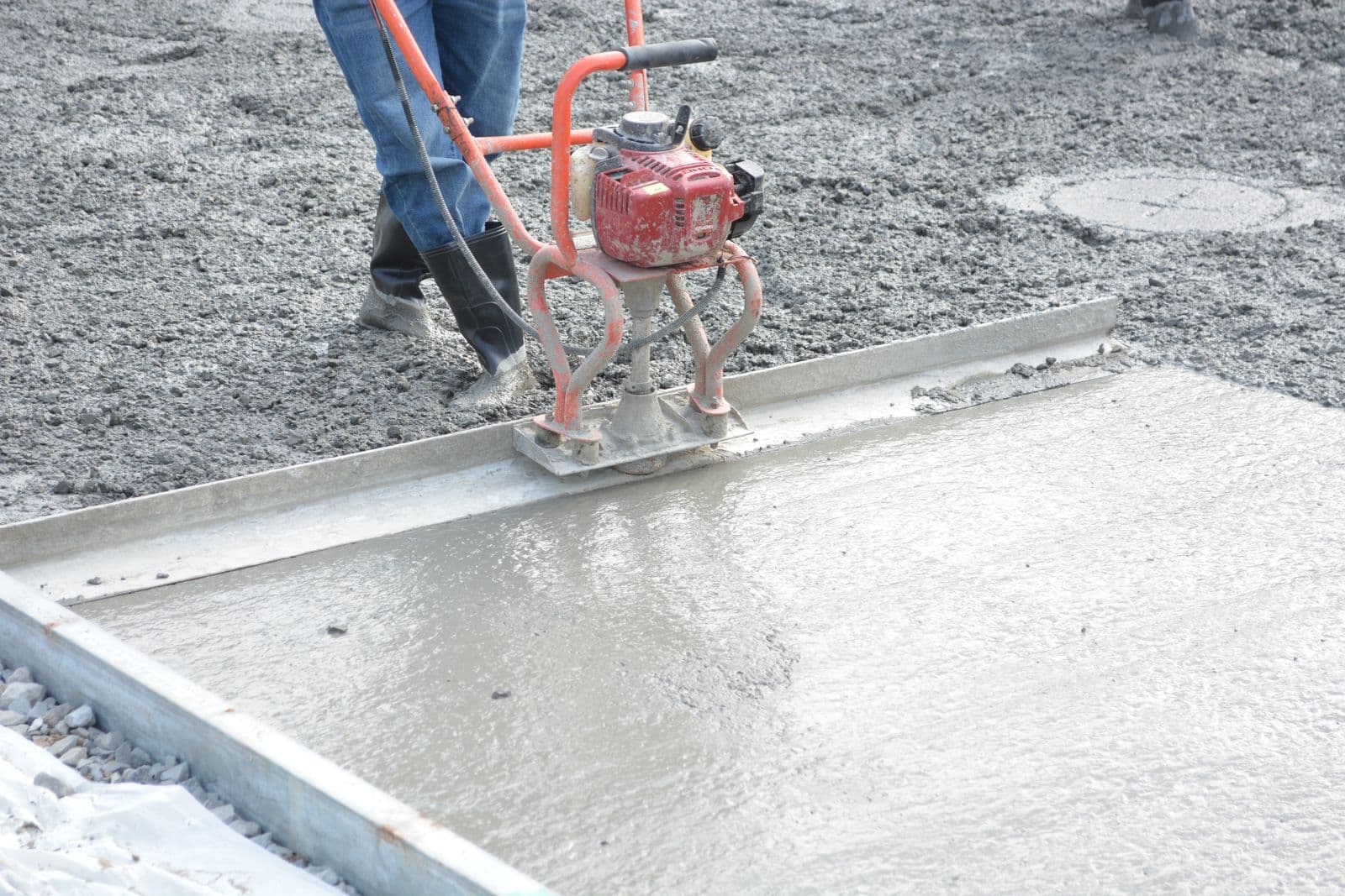 Concrete crew member power-troweling a freshly poured driveway slab